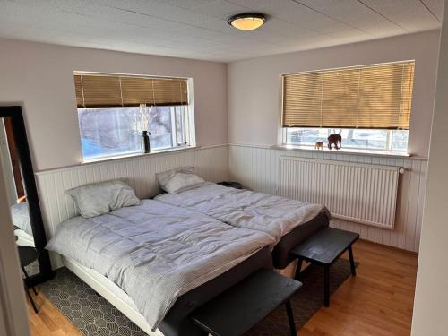 een slaapkamer met een groot bed en 2 ramen bij Stylish Apartment Retreat Near Downtown in Reykjavík