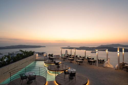a restaurant with a view of the ocean at sunset at Volcano View by Caldera Collection in Fira