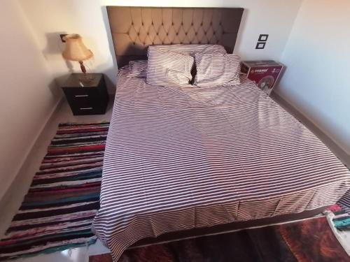 a large bed in a bedroom with a striped blanket at Aswan in Naj‘ al Maḩaţţah