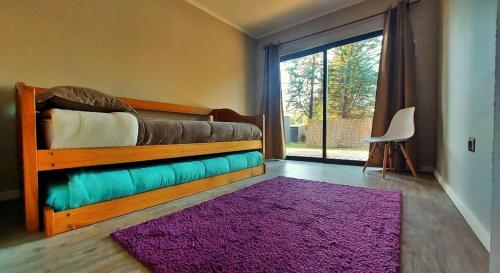 um quarto com uma cama com um tapete roxo e uma janela em Casa cercana a playas y bosque em Valparaíso