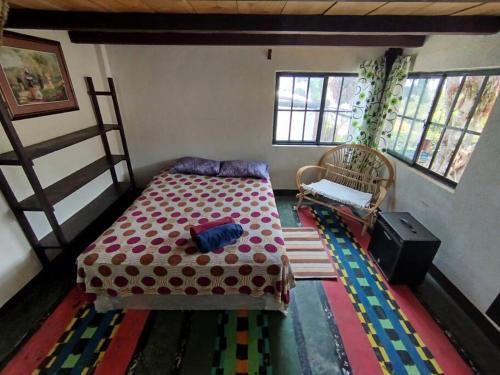 1 dormitorio con 1 cama y 1 silla en Casita Tz'ikin, en San Pedro La Laguna