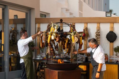 two men are preparing food on a grill at Volcano View by Caldera Collection in Fira
