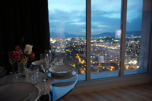 a table with glasses and a view of a city at Royal Kate SPA included 32nd floor in Skopje