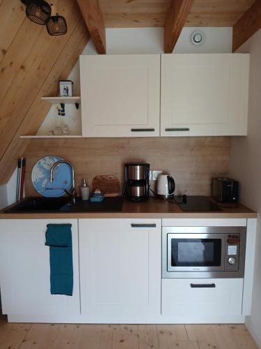 une cuisine avec des armoires blanches et un micro-ondes dans l'établissement Au Dolmen de Kerhus 
