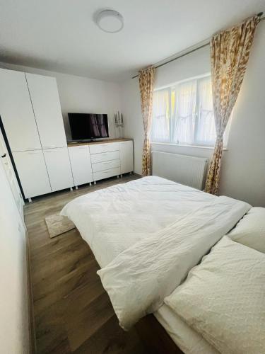 a bedroom with a large white bed and a television at Apartament Orizont in Suceava