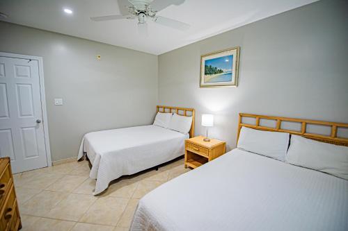a bedroom with two beds and a ceiling fan at Seven Mile Beach Resort in George Town