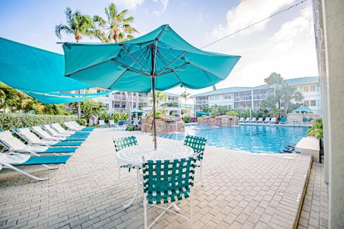 a table with an umbrella next to a swimming pool at Seven Mile Beach Resort in George Town