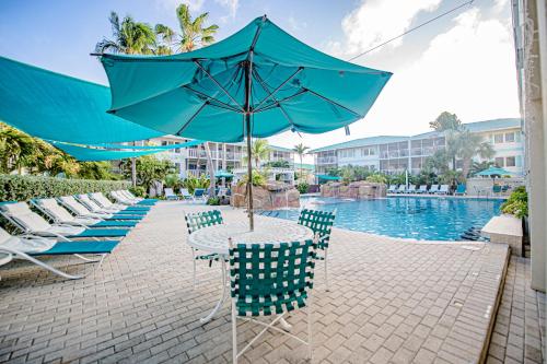 a table with an umbrella next to a swimming pool at Seven Mile Beach Resort in George Town