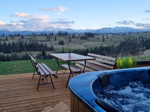 a hot tub on a deck with a table and chairs at Leszczyniański Domek in Biały Dunajec
