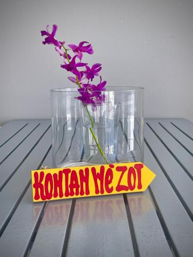 a vase with purple flowers sitting on a table at Villa Rose Marie Calme et Grands Espaces in Le François