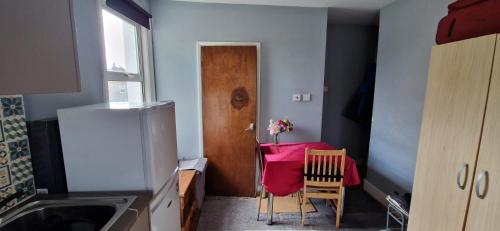 a small kitchen with a table and a wooden door at 29 tynemouth road in London