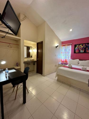 a bedroom with a bed and a desk and a tv at Hotel Barranquilla in Campeche