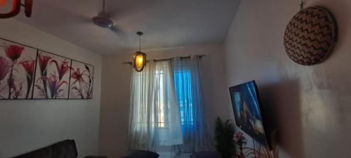 a living room with a window with a blue curtain at Bamburi One Bedroom Apartment in Mombasa