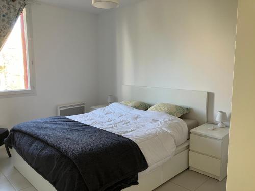 une chambre blanche avec un lit et une fenêtre dans l'établissement Le p'tit mas, à Cavalaire-sur-Mer