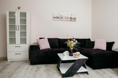 sala de estar con sofá negro y mesa en Rose Valley apartment en Kazanlŭk