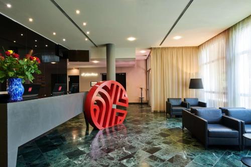 a lobby with a red chair in the middle of a room at NH Collection Prague in Prague