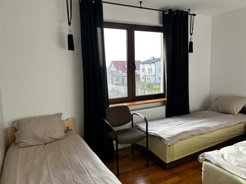 1 dormitorio con 2 camas, silla y ventana en Pokoje pokój u Bani en Skaryszew