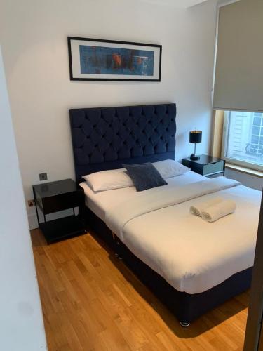 um quarto com uma cama grande e uma cabeceira azul em Sleep 4 in St James Piccadilly HY10 em Londres