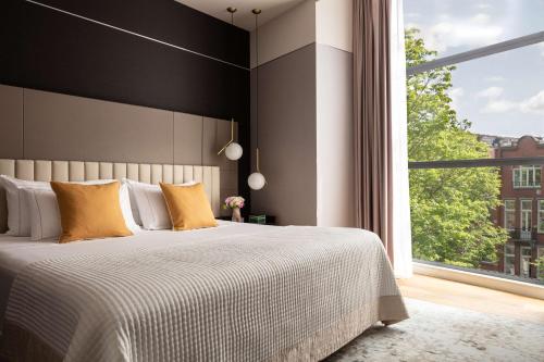 - une chambre avec un grand lit et une grande fenêtre dans l'établissement Anantara Grand Hotel Krasnapolsky Amsterdam, à Amsterdam