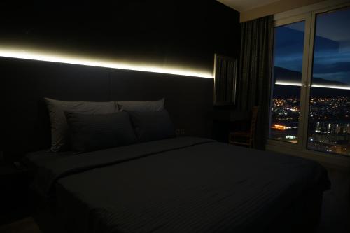 a bedroom with a bed and a window with a city skyline at Royal Kate SPA included 32nd floor in Skopje