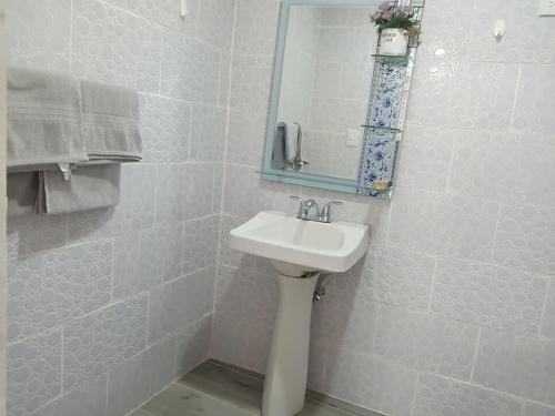 a white bathroom with a sink and a mirror at Villa rozenuda in Boca Chica