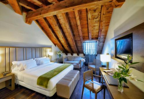 a bedroom with a large bed and a living room at NH Collection Madrid Palacio de Tepa in Madrid