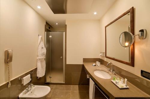 a bathroom with a sink and a toilet and a mirror at NH Bergamo in Bergamo