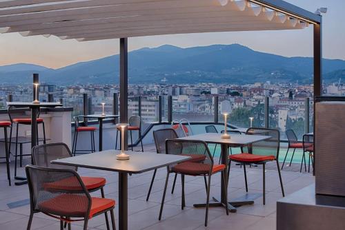 a restaurant with tables and chairs on a roof at NH Firenze in Florence