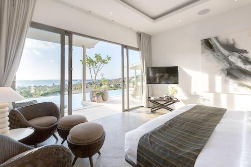 a bedroom with a bed and chairs and a television at Sunset Estates - Samui Luxury Villas in Choeng Mon Beach