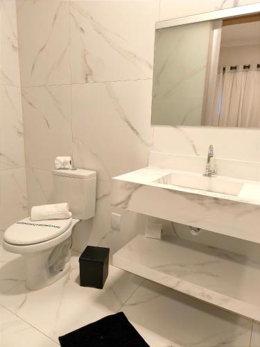 a white bathroom with a toilet and a sink at Villa Belo Quinto Spa & Spazzio Bloco 2 in Brotas