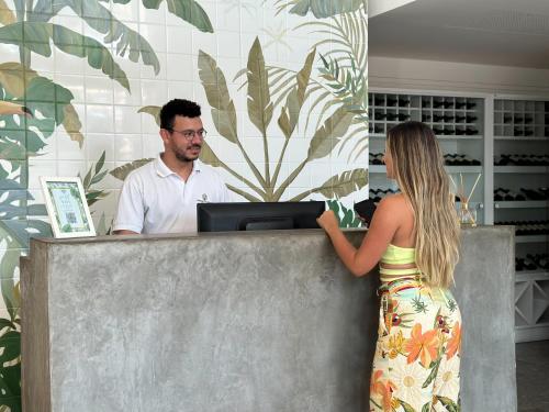Passagem Concept Hotel e Spa في كابو فريو: امرأة تقف عند صراف مع رجل