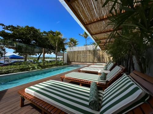 a row of chaise lounge chairs next to a swimming pool at Passagem Concept Hotel e Spa in Cabo Frio