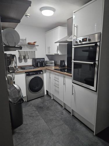a kitchen with white cabinets and a washer and dryer at Close to amenities in Weston-super-Mare