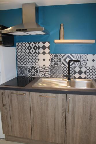 - une cuisine avec un évier et un mur bleu dans l'établissement Bel appartement neuf proche Disneyland et Paris- A proximité de la gare de Meaux, à Villenoy