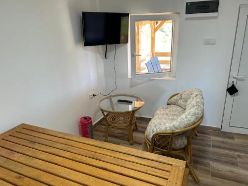 a living room with a table and chairs and a tv at Šumska kuća Ilija in Bogutovac