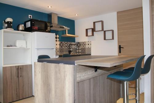 une cuisine avec un comptoir et des murs bleus dans l'établissement Bel appartement neuf proche Disneyland et Paris- A proximité de la gare de Meaux, à Villenoy