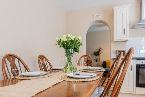 a dining room with a table with chairs and a vase of flowers at Brook Farm Barn in Frodsham