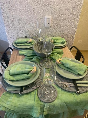 uma mesa com pratos verdes e copos de vinho em El trébol em Tunuyán