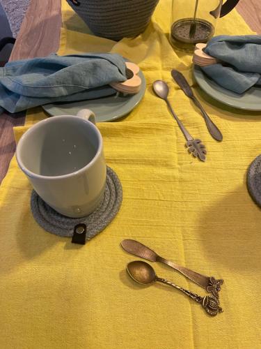 una mesa con una taza y cucharas sobre un mantel amarillo en El trébol en Tunuyán