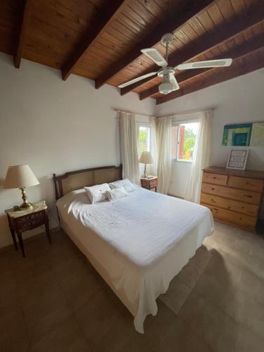 a bedroom with a white bed and a ceiling fan at Cabañas el Bierzo in Villa Cura Brochero