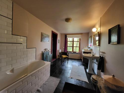 een grote badkamer met een bad en een wastafel bij Charming and cosy ART DECO house in old historic farm with private natural pool and gardens with hiking and cycling trails nearby in Sint-Truiden