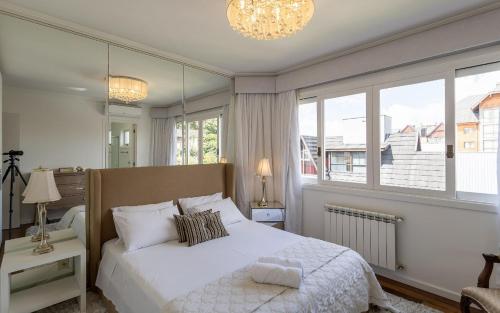 a bedroom with a white bed and a large window at LOCAR-IN GRAMADO - Boulevard in Gramado