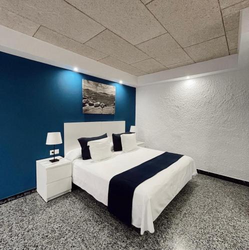 a bedroom with a large bed with a blue wall at Hotel Gri-Mar in Llança