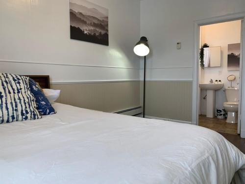 a bedroom with a white bed with a lamp and a sink at Large 1-bedroom Condo l Downtown l WiFi & Smart TV in Moose Jaw