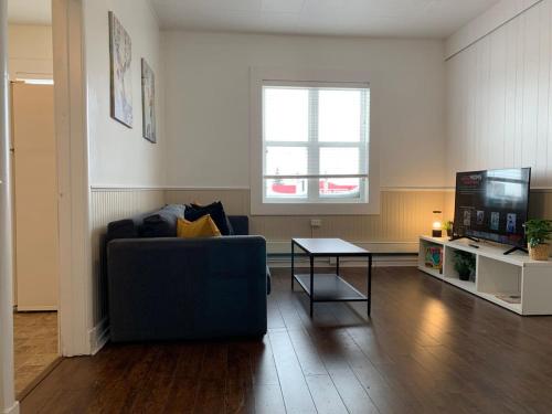 a living room with a couch and a table and a tv at Large 1-bedroom Condo l Downtown l WiFi & Smart TV in Moose Jaw