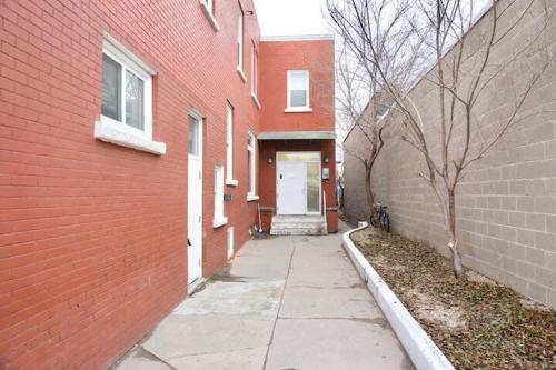a brick building with a white door and a sidewalk at Large 1-bedroom Condo l Downtown l WiFi & Smart TV in Moose Jaw