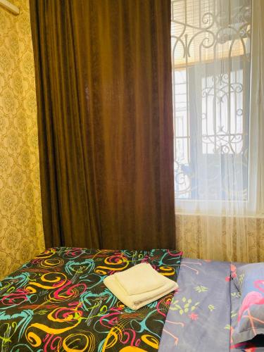 a bed with a comforter and a window at Anna'S Home in Kutaisi