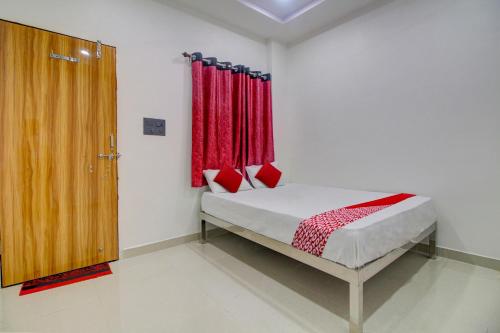 a bedroom with a bed with red curtains and a door at OYO Flagship Hotel Roman Inn in Nagpur