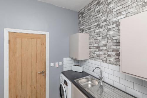 cocina con fregadero y pared de ladrillo en Central Apartment Darlington, en Darlington