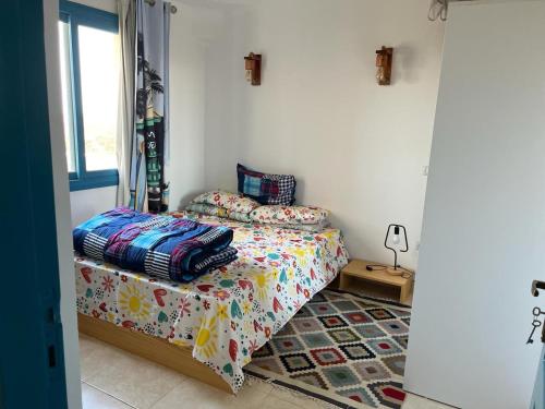 a bedroom with a bed with colorful sheets and a window at Cozy Chalet in Makadi Heights in Hurghada